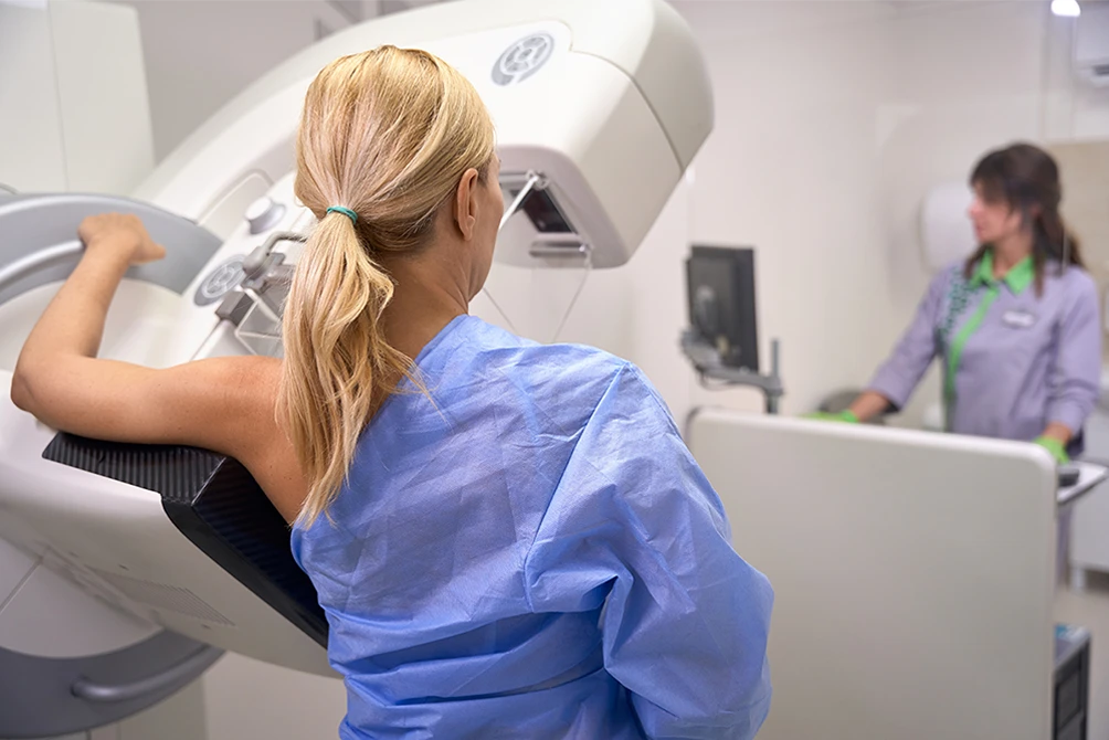Patient having a mammogram while a technologist assists