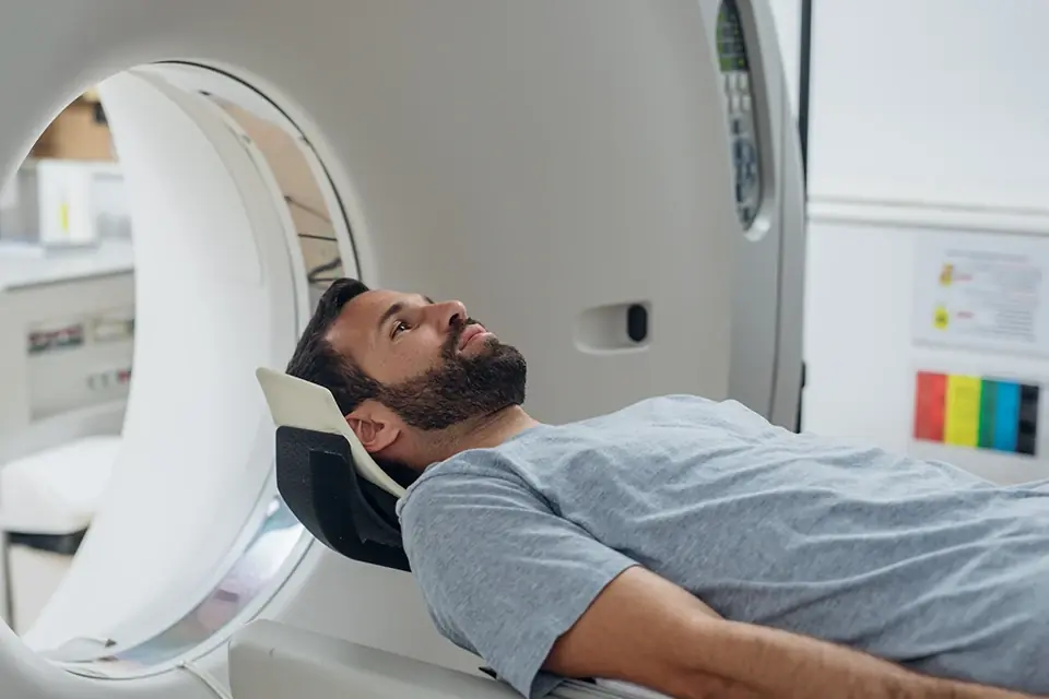 Technologist standing beside a patient lying in a scanner